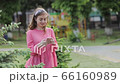 Pretty Young Woman Walking in the Park. Using her Mobile Phone. Chatting on it. Typing a Message. 66160989