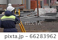 A man measures the distance on a building construction site with a laser rangefinder. 66283962