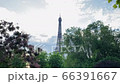 On a summer day, the most famous landmark in the world peeks through the green foliage, this is the Eiffel Tower. The camera slowly makes its way through the trees and rushes to the sights. 66391667