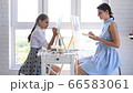 Mom and daughter paint at home in front of the window on easels and looked into the frame 66583061