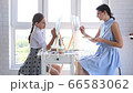 Mom and daughter paint at home in front of the window on easels 66583062