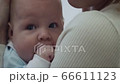 Mother holds and cradles her baby on hands in living room at home. 66611123