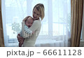 Young mother puts her little baby to sleep. 66611128