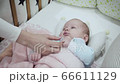 Mother's hand touches her newborn baby in the crib. 66611129