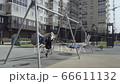 Smiling young woman swaying on swing on the playground in the city. 66611132