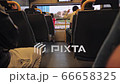 Unrecognized boy sits near a window in a double-decker modern bus. Palm trees and passing cars in 66658325