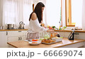 Asian woman with brightly smile doing sandwich and chatting to friends with tablet in the kitchen 66669074