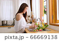 Cute asian woman wash vegetables and fruits to prepare for breakfast and look at camera in kitchen. 66669138