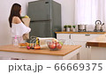 Cute woman holding paper bag walk into the kitchen,place on table and wash her hands with gel alchol 66669375