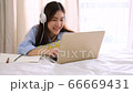 Asian woman wear headphones for listen course online with laptop and take notes. 66669431