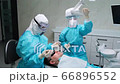 Woman dentist with the help of assistant works with a patient in dental office 66896552