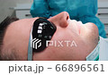 Closeup of the patient in black glasses lies on a dental chair during procedures 66896561