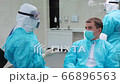 Patient listening the dentist. The assistant removes gloves in the background 66896563
