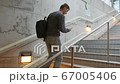 young man who climbs the stairs at the station and holds a phone in his hands 67005406