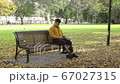 Alone men with yellow jacket using smartphone in the park of the fall. 67027315