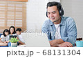 Asian father work at home with family, mother, daughter, and son sit together on sofa couch 68131304
