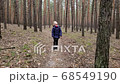 Little beautiful girl walks along the coniferous forest along the path to the camera. 68549190