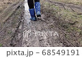 Woman walks along a rural dirty dirt road with puddles 68549191