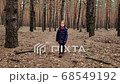 little girl walking along a path in a coniferous forest looking back at the camera, rear view 68549192