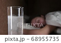 glass with a dissolving tablet on a bedside table. a girl waiting in bed 68955735