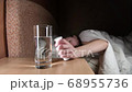 woman put a soluble pill with a medicine for hangover in a glass of water 68955736