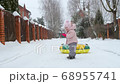 A small child tries to pull an inflatable circle on a rope on a snowy winter day 68955741