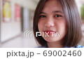 Slow motion of smiling Asian teen high school girl in uniform is standing in front of classroom. 69002460