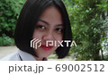 Slow motion of beautiful smiling Asian teen high school girl in white uniform relaxing in the park. 69002512