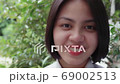 Slow motion of beautiful smiling Asian teen high school girl in white uniform relaxing in the park. 69002513