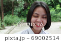 Slow motion of beautiful smiling Asian teen high school girl in white uniform relaxing in the park. 69002514