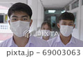 Slow motion of Asian students in a white uniform and wearing white masks are walking in the academy during the Coronavirus 2019 (Covid-19) epidemic. 69003063