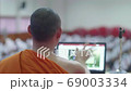 The monk of Theravada Buddhism in Thailand teach dharma by use laptop to projector screen on stage for students to sit neatly in the auditorium. 69003334
