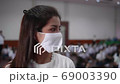 Asian female high school teacher and students on the semester start wearing a white mask, turn her face to look straight during the Coronavirus 2019 (Covid-19) epidemic. 69003390