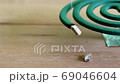 Green mosquito repellent burning and white smoke on wooden table with green blur light. 69046604