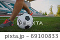 Close up of a male soccer player running with a soccer ball on the football field in the stadium 69100833