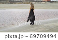 A girl in a black dress walks to the water on contaminated land amid a copper processing plant 69709494