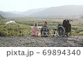Family leisure concept where young happy loving couple where one of them is invalid sitting on the hill and enjoying surrounding picturesque landscapes 69894340