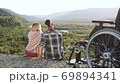 Attractive smiling happy romantic couple sitting near man's wheelchair on the mount on the wonderful landscapes background and kissing,slow motion 69894341