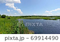 Landscape with lake surrounded with cane. Brushwood of rush in lake. Beautiful natural landscape with pond and clouds. Summer scenery 69914490