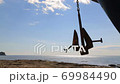 The ship's anchor weighs in the air above the shore. 69984490