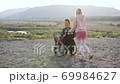 Attractive happy modern couple in love where handsome disabled man in wheelchair and his blond wife looking into the distance on the hill surrounded with picturesue nature at daytime 69984627