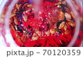 Brewing red tea with boiling water. Adding water to tea leaves with slices of apples, flowers. Making tea in a glass teapot. Tea ceremony. Close-up 70120359
