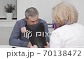 Mature man coughing at medical appointment with his doctor 70138472