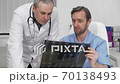 Mature male surgeon asking advice of his colleague on MRI scan of the patient 70138493