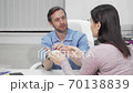 Male plastic surgeon showing silicone breast implants to a patient 70138839