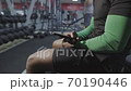 Unknown black man fast typing message in the phone in gym. Sport facilities on the background. Smartphone on hands. 70190446