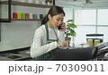 Young woman cafe owner talking on phone Take customer order in coffee shop 70309011