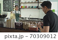 waitress delivers coffee and paper bags to customers at cafe counter. 70309012