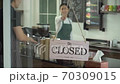 reopen the coffee shop after the quarantine.  young man who owner a retail restaurant is preparing cafe. Barista and the waitress manage sales at counter. 70309015
