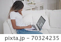 Young african woman sit on couch at home talk by webcam video conference call chatting with distance teacher 70324235